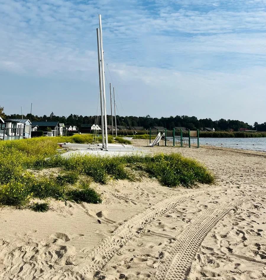 Owner-supplied photograph of a sandy lakeside shore, sailboats and family-friendly swimming water