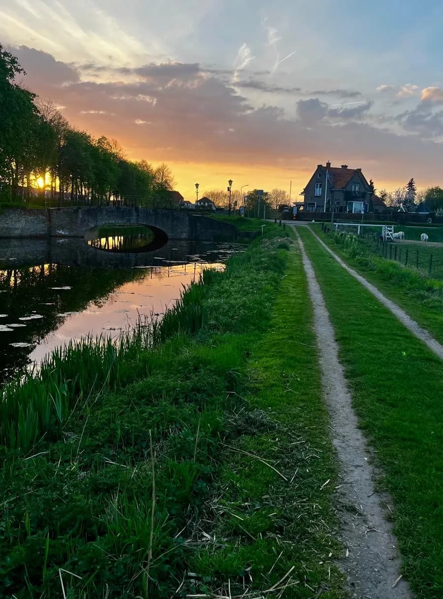 A peaceful Dutch waterway and country path at sunset